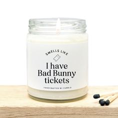 i have bad bunny tickets candle with matches on the table next to it and two black beads