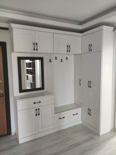 an empty room with white cabinets and drawers in the corner, including a mirror on the wall