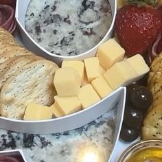 cheese, crackers and fruit are arranged in bowls