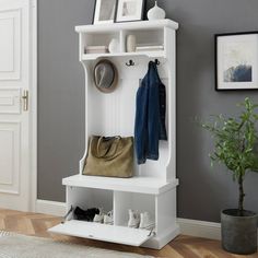 a white coat rack with shoes and purses on it next to a potted plant