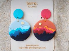 two colorful earrings with mountains on them sitting on top of a piece of paper that says terra by saran