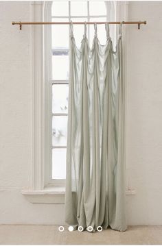 a window with curtains hanging in front of it and a curtain rod on the side