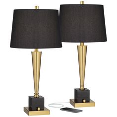 two black lamps with gold bases and a remote control