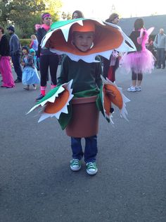 a little boy dressed up as a scarecrow in the street with other children around him