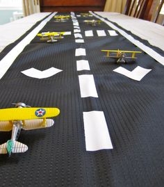 a toy airplane sitting on top of a long table covered in white and black paper