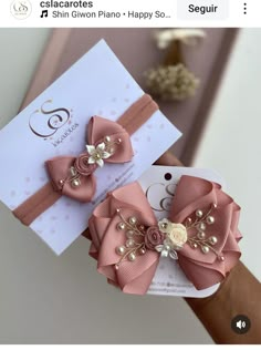 two pink bows with pearls on them sitting next to a white card that says g is for