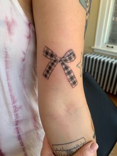 a woman's arm with a tattoo on it that has a checkered bow