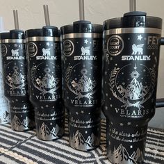 six stainless steel travel mugs are lined up on a table with black and white designs