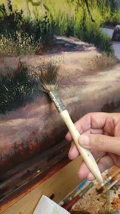 a person holding a brush in front of a painting