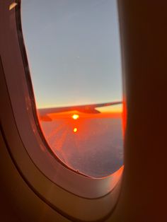 an airplane window with the sun setting in the sky as seen from it's wing