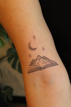 a person with a tattoo on their arm that has a mountain and moon above it