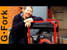 a man standing next to a red cart with a generator on it's back