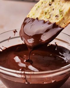 someone is dipping chocolate into a glass bowl