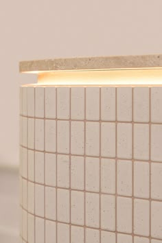 a light that is on in the middle of a tile wall with white and beige tiles