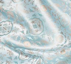 an image of a blue and gold fabric with flowers on it's side, as well as the background