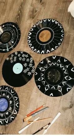 several black and white plates sitting on top of a wooden floor next to paintbrushes