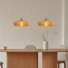 two pendant lights hanging over a wooden table