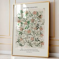 a framed poster with flowers on it in front of a white wall and gold trimmings