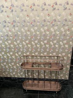 three tiered metal rack in front of floral wallpaper