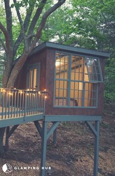 a tree house built into the side of a hill with lights on it's windows