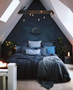 an attic bedroom decorated in grey and white with lights on the ceiling, bedding and pillows