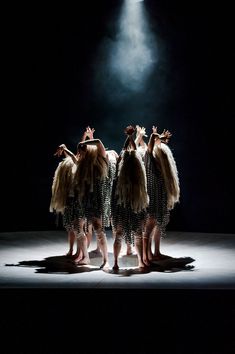 three women in dresses standing on a stage