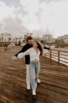 a man and woman dancing on a pier