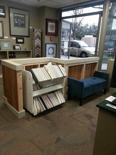 an office with many books on shelves and a blue chair in front of the window