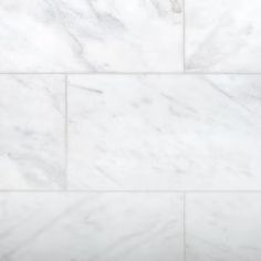 a white marble tile wall with some black dots on it