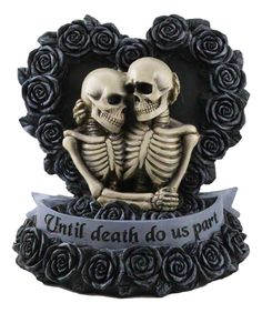 two skeleton figurines sitting next to each other in front of a heart shaped frame