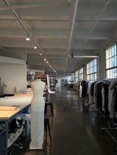 an empty clothing store with lots of clothes on hangers and tables in front of large windows