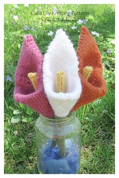 three knitted flowers in a jar on the grass