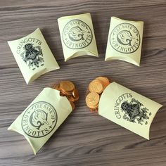 four pieces of paper with gold coins in front of them on a wooden table top