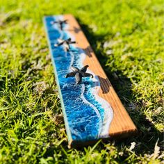 a surfboard with two turtles on it sitting in the grass next to the ocean