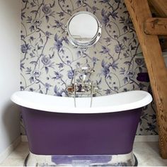 the bathroom is decorated in purple and has a floral wallpaper behind it, along with a claw foot bathtub