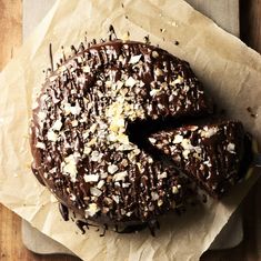 a chocolate covered doughnut sitting on top of a piece of wax paper next to a knife