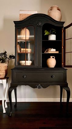 a black china cabinet sitting on top of a hard wood floor