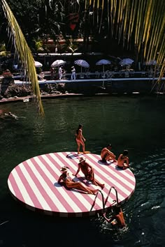 some people are in the water and one is on a pink and white striped raft