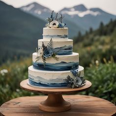 a three tiered cake with blue and white frosting sitting on top of a wooden table