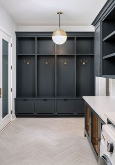 an empty laundry room with black cabinets and white counter tops, gold hooks on the wall