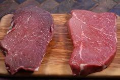 two pieces of raw meat sitting on top of a wooden cutting board