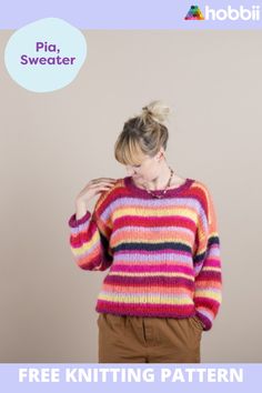 a woman standing in front of a wall wearing a colorful sweater