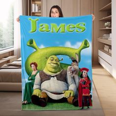 a woman holding up a personalized blanket with the characters from shrawns