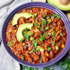 a purple bowl filled with chili and avocado