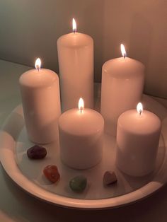 five lit candles on a plate with rocks