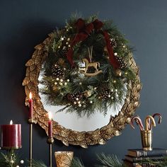 a christmas wreath is hung on the wall above a mantle with candles and other holiday decorations