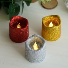 three glitter candles sitting next to each other on a table