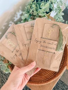 someone holding up some brown bags with writing on them in front of a potted plant