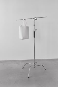 a white bag is hanging from a metal pole on a tripod in an empty room