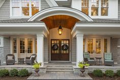 the front entrance of a house with chairs and wreaths